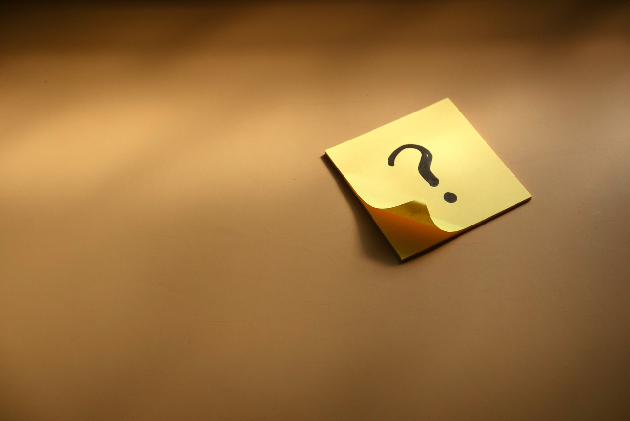 Questions and answer concept. Question mark written on paper. Brown silhouette shadow background.